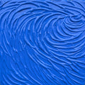 A close-up of a bright blue textured surface with thick, swirling impasto paint strokes.