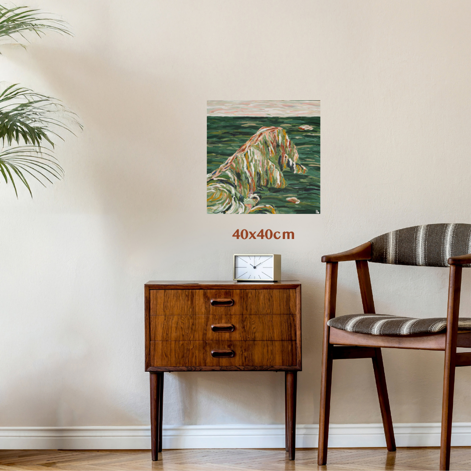 A framed or frameless wall art print showing a stylized green landscape with a winding river or path, displayed in a room above a wooden side table and chair. The image includes a '40x40cm' size marker. Art by Australian Abstract Artist Lucy Bauld. 