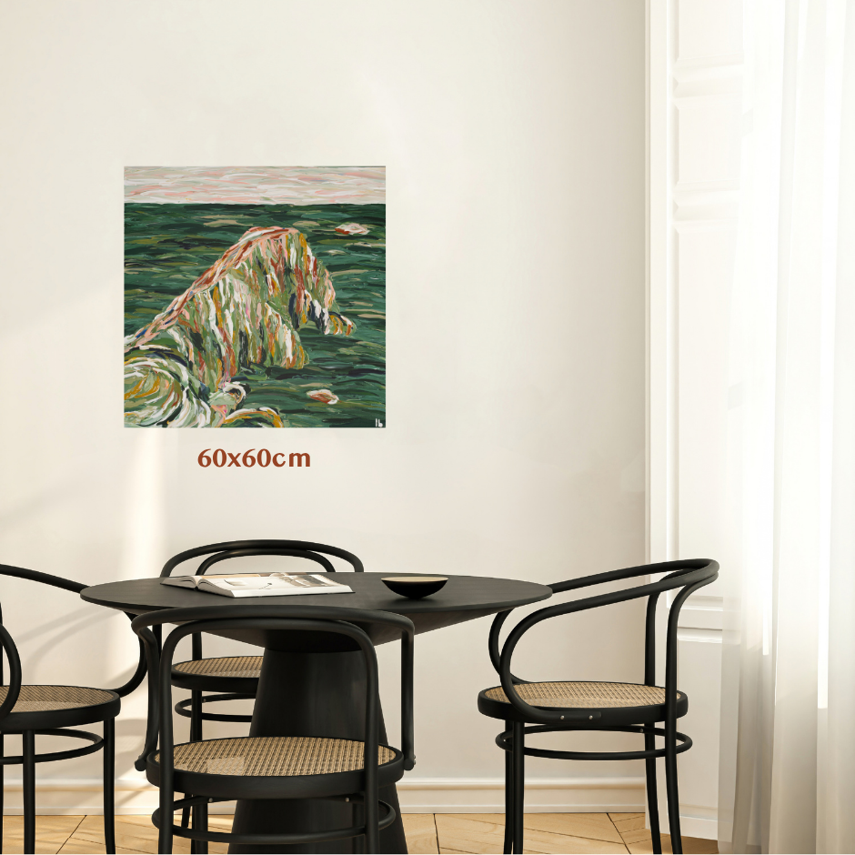 A 60x60cm square wall art print depicting a textured, impressionistic coastal landscape in green, beige, and orange tones, shown hanging on a white wall above a black dining table and chairs. Art by Australian Tasmanian abstract artist Lucy Bauld. 