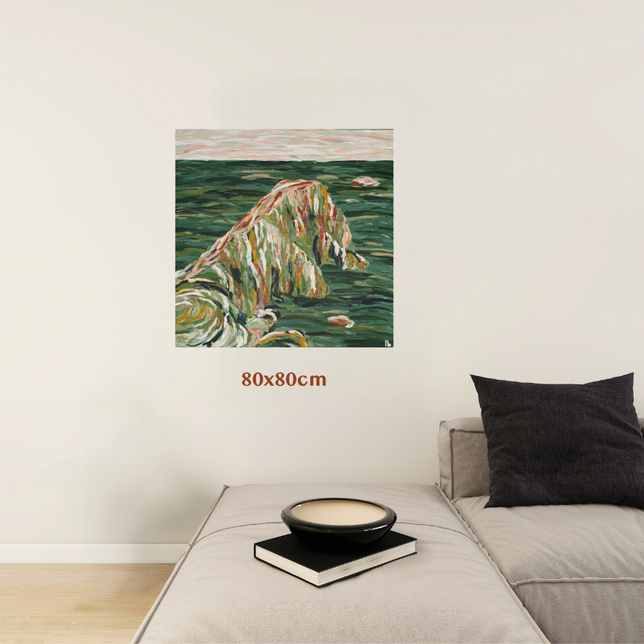 A framed or frameless wall art print showing an abstract coastal or rocky seascape in green, beige, and white tones, displayed above a light gray sofa in a modern room. Red text below the artwork reads 80x80cm. Art by Australian Tasmanian abstract artist Lucy Bauld. 