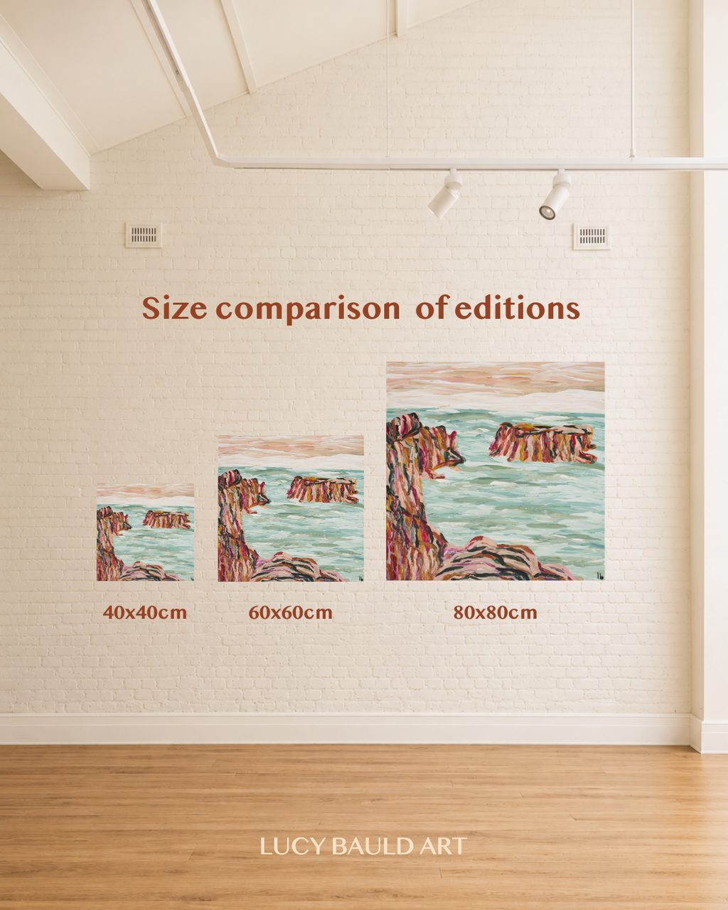 A size comparison display showing three versions of a coastal landscape art print on a white brick wall above a wood floor. The prints are labeled 40x40cm, 60x60cm, and 80x80cm, with the text 'Size comparison of editions' above them. Art by Australian abstract artist Lucy Bauld. 